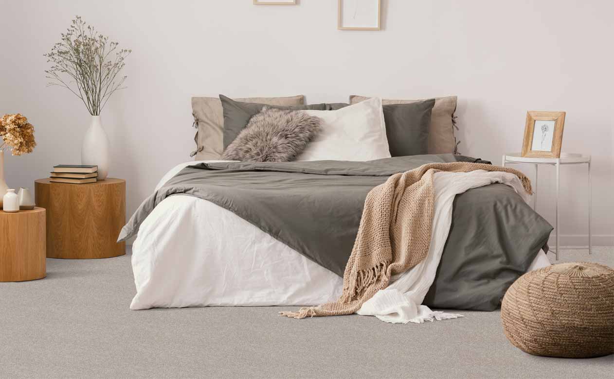 Bedroom with bed and wood side tables, beige carpeted floor